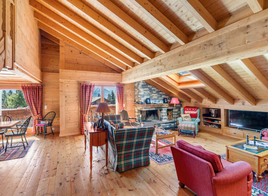 Experience rustic charm in this beautifully appointed living room, featuring a grand stone fireplace and exposed wooden beams that create a warm, inviting atmosphere.