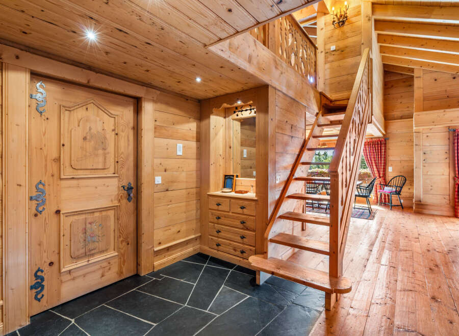 Step into a charming alpine retreat featuring rustic wooden interiors and a grand staircase.