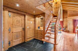 Step into a charming alpine retreat featuring rustic wooden interiors and a grand staircase.