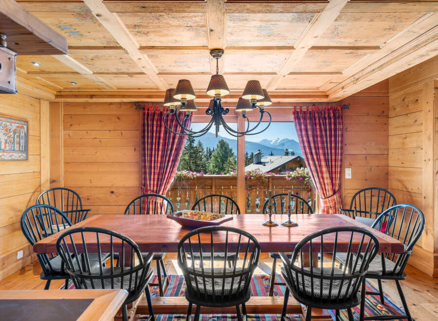 Experience rustic charm in this dining room, featuring a large wooden table surrounded by black Windsor chairs.