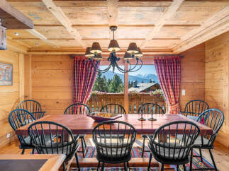 Experience rustic charm in this dining room, featuring a large wooden table surrounded by black Windsor chairs.