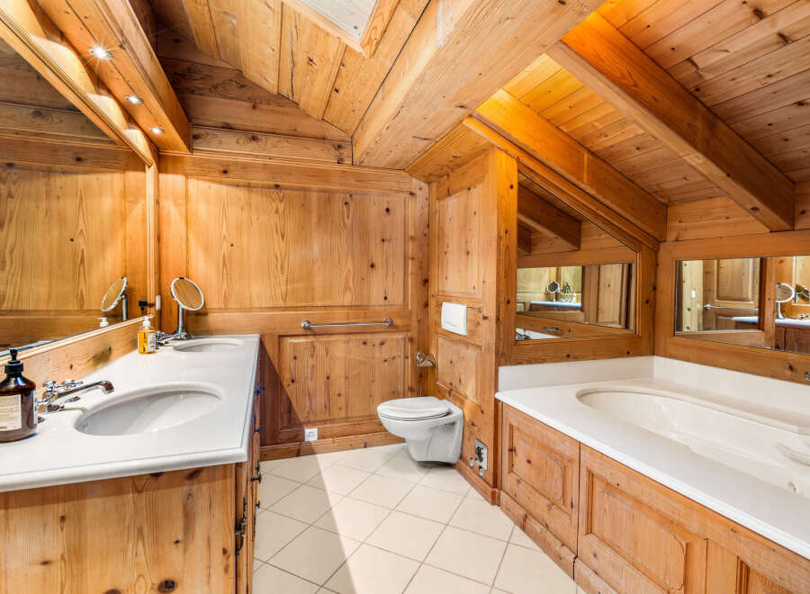 Experience rustic luxury in this charming wooden bathroom, featuring a spacious double vanity with marble countertops and elegant chrome fixtures.