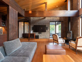 Experience rustic luxury in this stunning living room, featuring a soaring vaulted ceiling with exposed wooden beams and a dramatic stone accent wall.