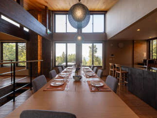 Experience luxurious dining in this spacious home, featuring a grand wooden dining table set for an intimate gathering.