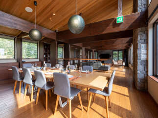 Experience elegant dining in this spacious room, featuring a large wooden table set for a feast and surrounded by comfortable grey chairs.