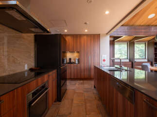 Experience modern luxury in this stunning kitchen, featuring sleek wooden cabinetry and a spacious island with a built-in sink and faucet.