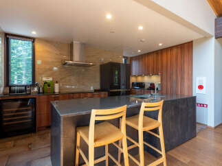 Experience modern living in this stunning kitchen featuring sleek wooden cabinetry and a spacious island with bar seating.
