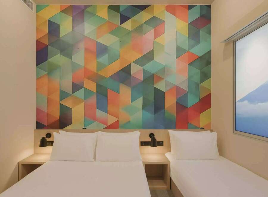 Experience modern comfort in this hotel room featuring a vibrant, geometric accent wall that adds a pop of color and contemporary style.