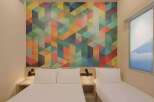 Experience modern comfort in this hotel room featuring a vibrant, geometric accent wall that adds a pop of color and contemporary style.