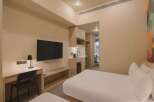 Experience modern comfort in this hotel room featuring two plush beds, a convenient kitchenette with a sink and mini-fridge, and a dedicated workspace with a desk and lamp.