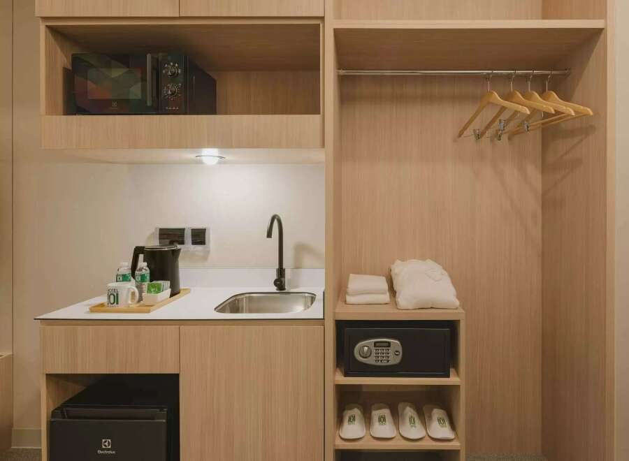 This hotel room offers a convenient kitchenette area complete with a microwave, sink, and electric kettle, perfect for preparing simple meals or hot beverages.