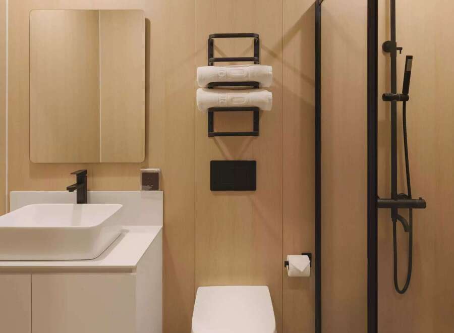Experience modern comfort in this sleek bathroom featuring a floating vanity with a vessel sink and a matte black faucet.