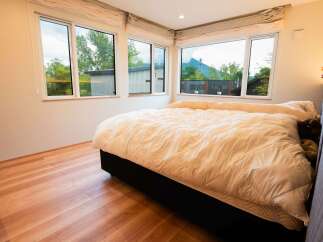 Experience comfort and style in this beautifully appointed bedroom, featuring a plush duvet and expansive windows that flood the space with natural light.