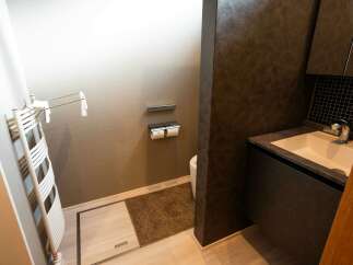 Experience modern comfort in this stylish bathroom featuring a sleek vanity with a built-in sink and a convenient towel warmer.