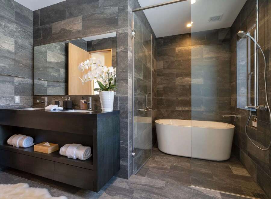 Experience modern luxury in this stunning bathroom, featuring a sleek dark wood vanity with double sinks and ample storage.