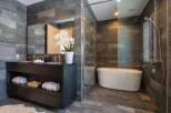 Experience modern luxury in this stunning bathroom, featuring a sleek dark wood vanity with double sinks and ample storage.