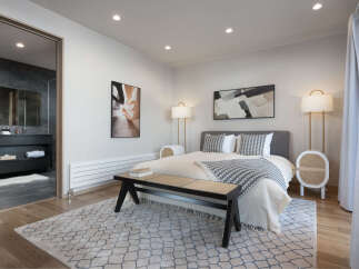 Experience modern comfort in this beautifully appointed bedroom, featuring a plush king-sized bed adorned with elegant patterned pillows and a cozy throw.