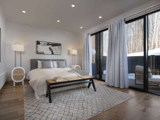 Experience luxury in this beautifully appointed bedroom featuring a plush king-sized bed, elegant bedside lamps, and a stylish woven bench.