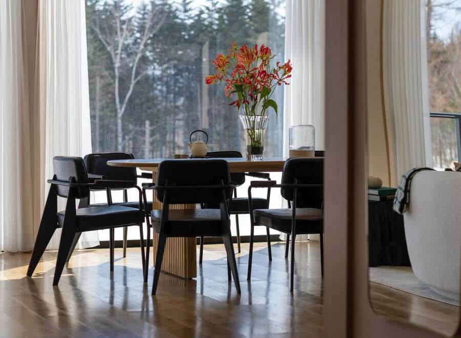 Experience elegant dining in this home, featuring a round wooden table surrounded by sleek black chairs.
