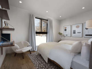 Experience serene winter views from this beautifully appointed bedroom, featuring two comfortable beds dressed in crisp white linens.