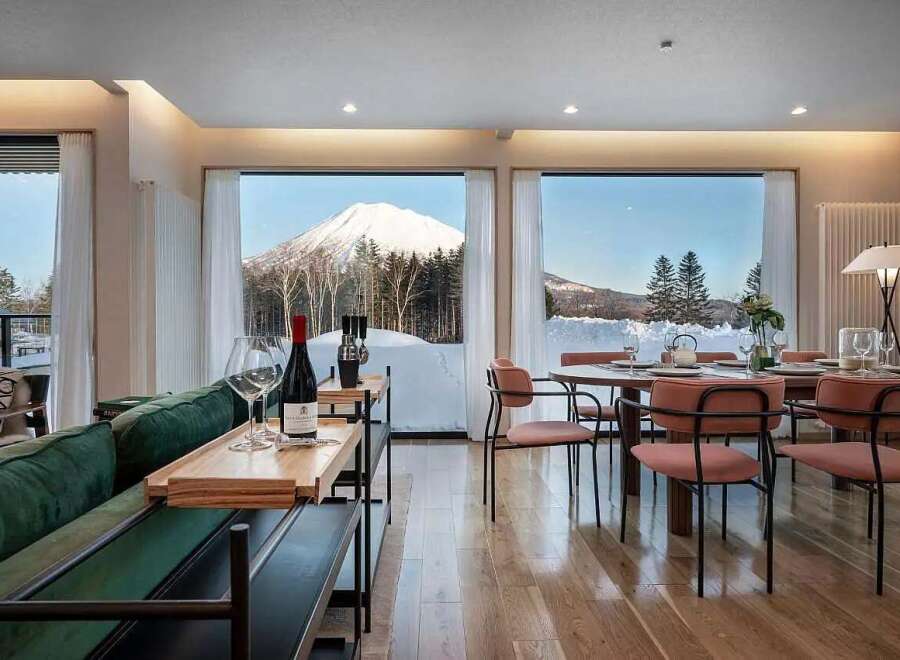 Experience breathtaking mountain views from this luxurious living space, featuring a plush green sofa and a sophisticated dining area.