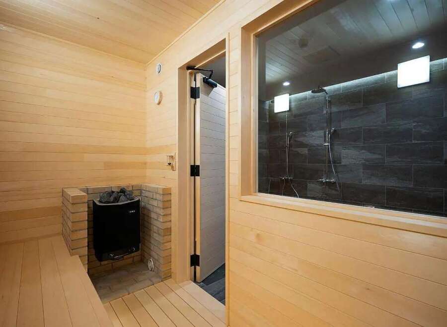 Experience ultimate relaxation in this modern sauna featuring a traditional wood-paneled interior and a built-in brick-encased heater.
