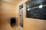 Experience ultimate relaxation in this modern sauna featuring a traditional wood-paneled interior and a built-in brick-encased heater.
