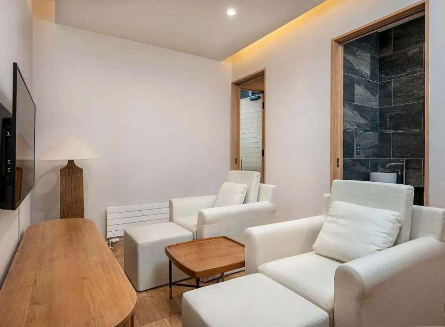 Experience ultimate relaxation in this serene living space, featuring plush white armchairs with accompanying ottomans perfect for unwinding.