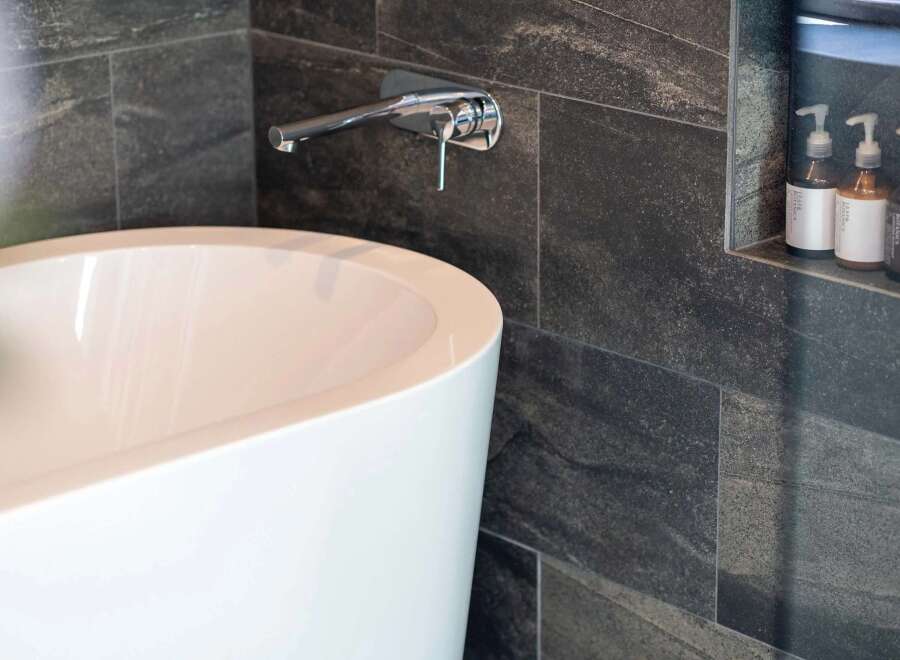 Experience modern luxury in this bathroom, featuring a sleek freestanding bathtub and a minimalist wall-mounted faucet.