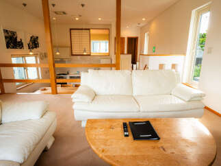 Experience modern living in this spacious open-plan apartment, featuring a comfortable white leather sofa and a rustic wooden coffee table.