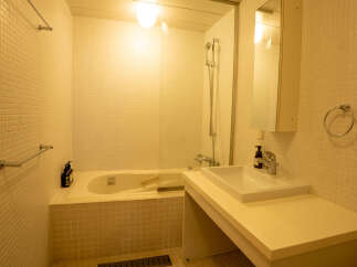 This modern bathroom features a clean and minimalist design with white tiled walls and a spacious bathtub.