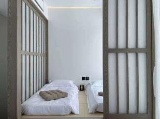Experience serene living in this minimalist bedroom featuring two twin beds with crisp white linens and a calming neutral palette.