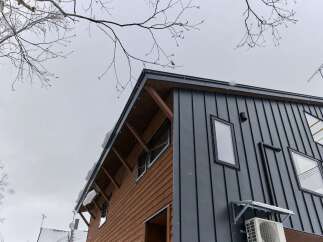 Experience modern living in this striking architectural home, featuring a unique blend of warm wood siding and sleek dark metal cladding.