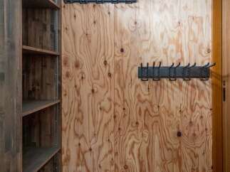 This entryway features a practical storage solution with a tall wooden shelving unit and multiple wall-mounted coat racks.