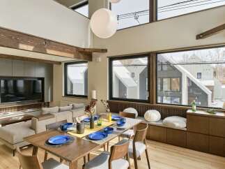 Experience modern living in this spacious dining and living area, featuring a stunning wooden beam ceiling and expansive windows that offer breathtaking views.