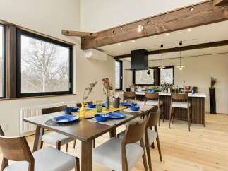 Experience modern living in this open-concept dining and kitchen area, featuring a spacious wooden dining table set for a meal and a sleek kitchen island with bar seating.