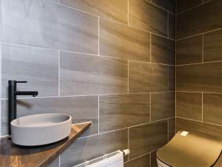 Experience modern luxury in this stylish bathroom featuring large-format grey stone tiles on the walls and floor.