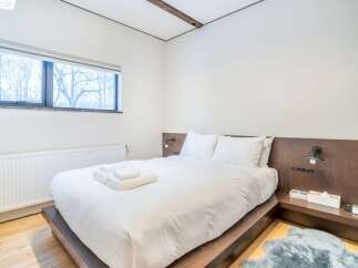 Experience comfort and style in this beautifully appointed bedroom, featuring a plush queen-sized bed with crisp white linens and two supportive pillows.