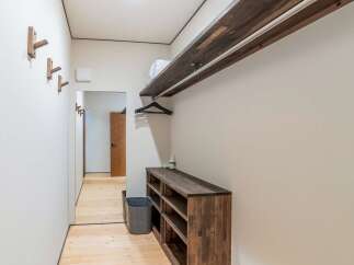 Discover this charming entryway featuring a minimalist wooden coat rack and a sleek, dark wood shoe cabinet.