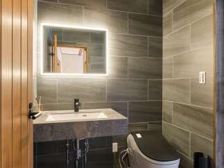 Experience modern luxury in this stunning bathroom, featuring a sleek floating vanity with a stone countertop and a backlit mirror.