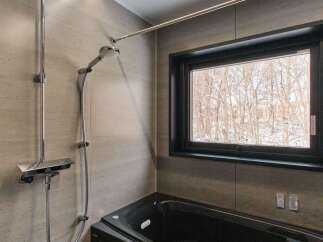 Experience ultimate relaxation in this modern bathroom featuring a sleek black bathtub and a luxurious rainfall showerhead.