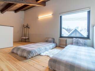 Experience cozy living in this charming attic bedroom, featuring two twin beds with plaid bedding and a fluffy white rug.