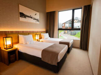 Experience comfort and style in this modern hotel room featuring two twin beds, perfect for solo travelers or friends.