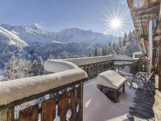 Experience breathtaking mountain views from this charming alpine chalet's snow-covered balcony.