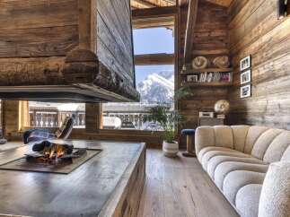 Experience rustic luxury in this stunning mountain chalet living room, featuring a grand fireplace and breathtaking panoramic views of snow-capped peaks.