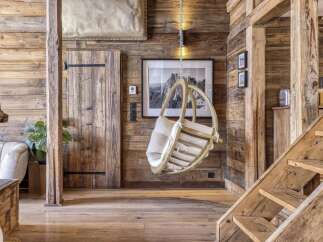 Experience rustic charm in this mountain retreat, featuring a cozy wooden interior with exposed beams and a unique hanging chair.