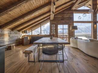 Experience luxurious mountain living in this stunning chalet, featuring a spacious open-plan living area with a rustic wooden interior and breathtaking panoramic views of snow-capped peaks.