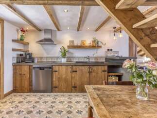 Experience rustic charm in this cozy kitchen featuring exposed wooden beams and charming country-style cabinetry.