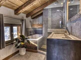 Experience rustic charm and modern comfort in this mountain bathroom, featuring a deep soaking tub and a sleek concrete vanity.