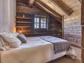 Experience rustic charm in this cozy mountain bedroom, featuring exposed wooden beams and walls that evoke a sense of warmth and tranquility.
